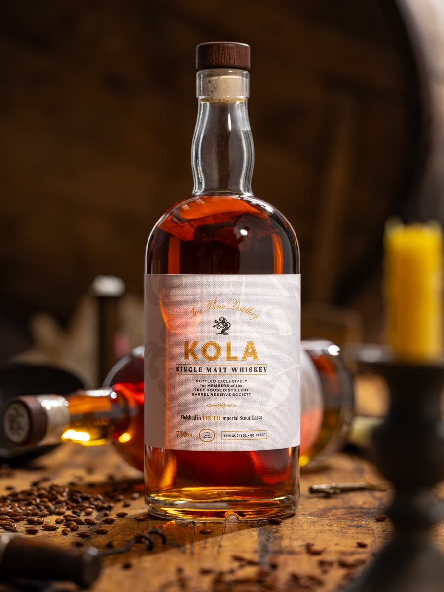 A bottle of KOLA Single Malt Whiskey on a barrel-room table